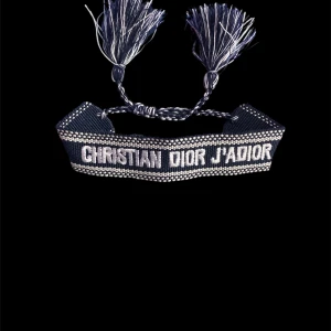 mörk Blått armband Christian Dior J'Adior - Snyggt blått armband från Christian Dior med texten 'J'Adior' broderad i vitt. Armbandet har flätad knytning och dekorativa tofsar i ändarna. Perfekt accessoar för att lyfta din outfit med en lyxig touch.