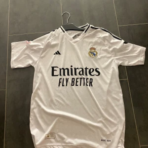 Real Madrid fotbollströja - Tja, säljer real madrid hemmaplan t shirt, bellingham på ryggen. Ej äkta så säljer för billigt. Storlek M true to size, Aldrig använd. Fraktar samma dag eller dagen efter. Hör av er vid intresse💯