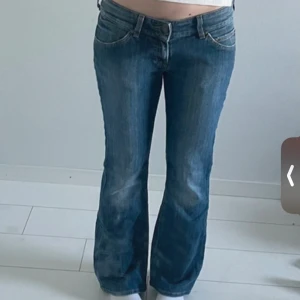 Blå bootcut jeans från Lee - Snygga blå jeans från Lee med klassisk bootcut passform och låg midja. Jeansen har slitningar framtill, fem fickor och detaljerade sömmar med Lee-logga på baksidan. Passar nog någon som är ca 160-165