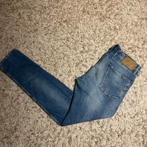 Replay anbass jeans slim fit herr w32  - Replay anbass jeans i slim passform. Storlek W32. Skön wash o små slitningar. Mycket bra skick övrigt, förutom två bälteshåller har lossnat nedifrån på baken, den i mitten fungerar, se bild. Postas samma dag som köp eller dagen därpå🙌💯