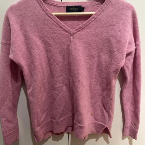 Rosa merinoullströja från Morris Lady - Supermjuk rosa tröja i 100% merinoull från Morris Lady. V-ringad modell med långa ärmar och ribbade muddar. Snygg detalj med guldfärgad logga vid nederkanten och broderad symbol på ärmen. Perfekt för lager-på-lager under kyliga dagar. Älskar men anvönder tyvärr inte längre… superskön iaf💓💓