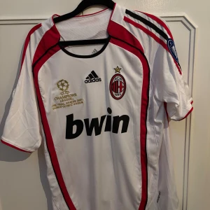 AC Milan Kaka Champions League tröja - AC Milan bortatröja från Champions League-finalen 2007 med Kaka 22 på ryggen. Vit med röda och svarta detaljer, Adidas-logga, klubbmärke och Champions League-märke på ärmen. Tillverkad i lätt och ventilerande material. Var för stor så har aldrig använd denna, hoppades på att växa!