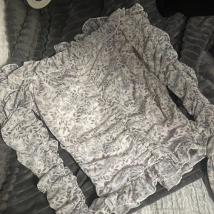 Blommig top  - Blommig top axelös med volang nere vid ärmen storlek S