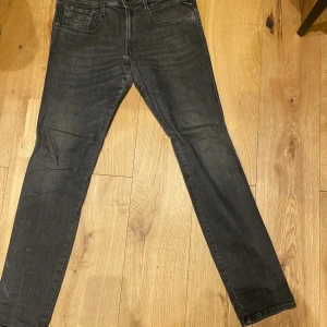 Replay Anbass svarta jeans, stl 33 - Snygga svarta Replay Anbass jeans i klassisk femficksmodell. Jeansen har en smal passform med raka ben och diskret tvättad look. Perfekta för dig som gillar stilrena och moderna jeans med en bekväm känsla.