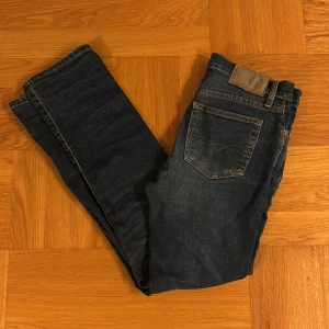 Mörkblå slim jeans från Polo Ralph Lauren strl. 16/160 - Snygga mörkblå jeans från Polo Ralph Lauren med klassisk femficksdesign och guldfärgade sömmar. Jeansen har dragkedja, raka ben och en stilren look. 