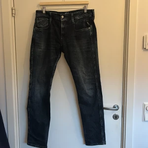 Replay Anbass jeans i mörkblå denim - Snygga Replay Anbass jeans i mörkblå tvätt med slitningar och klassisk femficksdesign. Tillverkade i ekologisk bomull för en skön känsla och hållbar stil. Raka ben och diskreta detaljer gör dem till ett självklart val för dig som gillar en clean look.