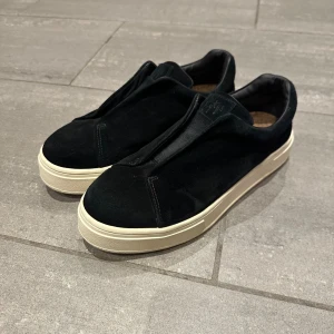 Svarta Eytys sneakers i mocka, strl 40 - Säljer ett par svarta sneakers från Eytys i storlek 40. Skorna har en chunky vit platt sula och är tillverkade i mjuk mocka med minimalistisk design utan snörning. Perfekt för dig som gillar stilrena och moderna sneakers. Perfekt nu till hösten och vintern. Nypris 2000kr