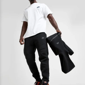 Svarta nike tech fleece från Nike - Svarta mjukisbyxor från Nike med broderad logga på benet, elastisk midja med snörning och dragkedjeförsedda fickor. Aldrig använts 
