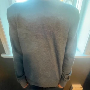 Grå stickad tröja Stenströms - Snygg grå stickad tröja från Stenströms med ljusa armbågslappar som ger en chill och stilren vibe. Tröjan är från början i strl M men har krympt i tvätten så den passar XS