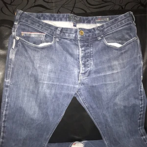 Blå jeans från Armani Jeans, Regular Slim - Snygga blå jeans från Armani Jeans i modellen Regular Slim. Klassisk femficksdesign med mässingsfärgad knapp och diskreta röda detaljer vid fickorna. Bakficka med ikonisk Armani-logga. Jeansen har en rak passform och är tillverkade i mjukt denimtyg.