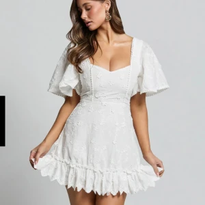 Vit student/sommar klänning - Superfin vit kort klänning med broderade blommor, volangkant och u-ringning. Klänningen har vida korta ärmar och markerad midja. Söt spetsdetalj längs kanterna. Den är helt oanvänd med lappen kvar då den va för liten. Storlek 38(liten i storleken) jag bär i vanliga fall M och den va en storlek för liten. Nypris 1000kr (inkl frakt) 