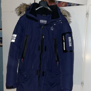 Vinterjacka  - Säljer en mörkblå parkajacka från Windy Peak med huva och snygg fuskpäls. Anledningen till att jag säljer jackan är för att den ligger bara i garderoben och jag aldrig användning till den. Jackan är i topp skick, så gott som ny kan man säga. Den är varm o skön och passar perfekt till den kalla vintern som är på väg. Skriv för fler frågor eller funderingar. Önskar er allt gott//Kevin.