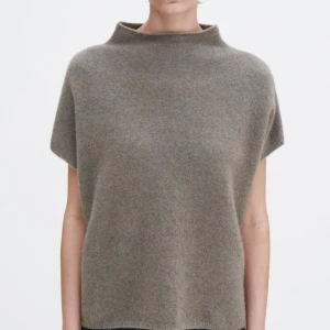 Beige stickad polotopp från Filippa K - Säljer en beige stickad polotopp från Filippa K. Toppen har en hög krage, ärmlös design och loose passform. Materialet är mjukt och fluffigt.