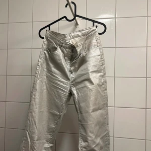 Silvriga jeansbyxor från C.W. strl 36 - Snygga silvriga jeansbyxor från C.W. i storlek 36. Byxorna har klassisk femficksmodell, raka ben och dragkedja framtill. Materialet är glansigt och ger en futuristisk vibe, perfekt för dig som vill sticka ut med din stil.