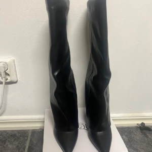 Svarta höga boots  - Säljer ett par svarta höga stövlar i slätt skinnimitation. Stövlarna har spetsig tå och  klack. Storlek 38 i bra skick, säljer pga de inte kommer till användning 