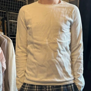 Vit långärmad bomullströja - En enkel och stilren vit långärmad tröja i mjuk bomull. Tröjan har rund hals och en normal passform som sitter skönt på kroppen. Perfekt för dig som gillar minimalistisk stil och vill ha något som funkar till många olika outfits. Tröjan har små fläckar på höger axel. Pris kan diskuteras!