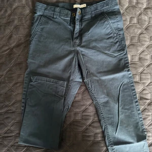 Mörkgrå byxor från Name It - Snygga mörkgrå byxor från Name It i storlek 140. Byxorna har klassiska fickor på sidan, bälteshällor och dragkedja med knapp. Perfekta för en avslappnad och cool stil. Tillverkade i mjuk bomull för extra komfort.