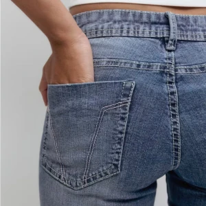 Blå bootcut jeans med låg midja - Snygga blå jeans med bootcut-modell och låg midja. Jeansen har klassiska fickor bak och fram, samt ljus tvätt med subtila slitningar. Perfekta för en avslappnad och trendig look. Köparen står för frakt.
