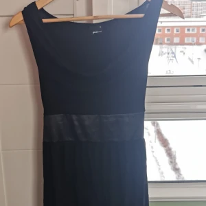 Svart klänning med sidenband Gina Tricot - En väldigt mysig svart klänning från Gina Tricot. Modellen är ärmlös, har rund halsringnig och ett brett sidenband i midjan som knyts baktill. Väl använd, kan finnas något litet hål men hittade inget när jag kikade. Säljer för att jag inte använder den längre