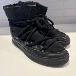 Svarta boots från Inuikii i mocka och skinn - Säljer ett par svarta Inuikii boots med grova snören och rund tå. Skorna är tillverkade i en mix av mocka och skinn, med mjuk insida och robust yttersula. Perfekta för kalla dagar och har en snygg urban look.