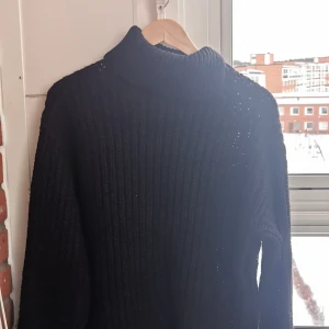 Svart polotröja från Lindex, stickad - Mysig svart stickad polotröja från Lindex i storlek S. Tröjan har en hög krage och är ribbstickad för en snygg och enkel look. Perfekt för kyliga dagar och passar till allt i garderoben.