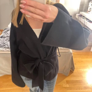 Svart kofta med knyte i midjan  - Koftan kommer från Gina Tricot och köptes för två veckor sedan. Den är i stolek M, och jag upplever den något stor så därför säljer jag den. Hör gärna av dig vid frågor🤎