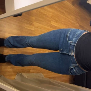 Blå bootcut jeans med normal passform - Snygga blå jeans med klassisk bootcut och normal passform. Jeansen har fem fickor, bälteshällor och dragkedja med knapp framtill. Materialet är slitstarkt jeans och färgen är en djup blå ton som passar till det mesta.