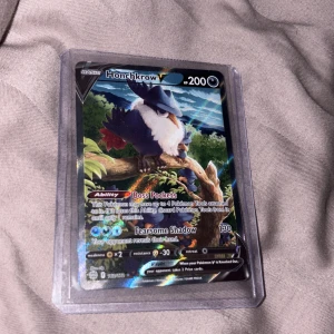 Honchkrow V Pokémonkort - Coolt och glittrande Honchkrow V-kort för Pokémon TCG! Perfekt för samlare och spelare som vill boosta sin lek med unika förmågor. Kortet är i skyddande plastfodral och har snygg design som sticker ut i samlingen.