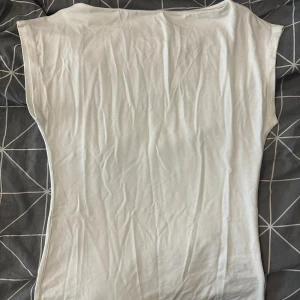 Vit ärmlös topp från 157 - Säljer en enkel och stilren vit topp från 157 i storlek XS. Toppen är ärmlös med rak passform och har en mjuk känsla i bomullsmaterial. Tröjan är köpt för ca 2 veckor sedan och har aldri använt den. Den passar både XS och S.