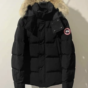 Svart dunjacka med päls från Canada Goose - Svart dunjacka från Canada Goose med fluffig päls på huvan och klassisk logga på ärmen. Jackan har dragkedja, knappar och quiltad design. Perfekt för kalla dagar med sin tjocka stoppning och snygga look. Den är helt ny säljer pågrund av att den är för stor och vill köpa en mindre storlek. Pris kan diskuteras vid snabba affärer.
