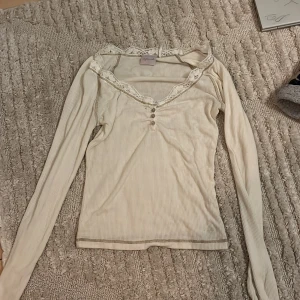 Vit långärmad tröja från Urban Outfiters - Supersöt vit ribbad topp från afound med lång ärm och u-ringad hals. Gullig spets med tre söta knappar. 