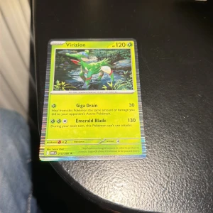 Virizion - Cool Pokémon-kort med Virizion! Perfekt för dig som samlar eller spelar Pokémon TCG. Kortet har snygg design och specialattacker som Giga Drain och Emerald Blade. Ett måste för alla Pokémon-fans som vill utöka sin samling med ett gräslegendariskt kort.
