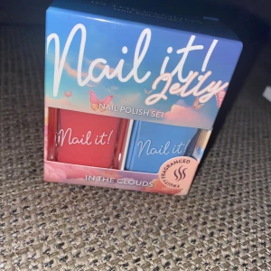 Nail it! Jelly nagellackset - Nagellackset med två färger: en korallröd och en ljusblå. Båda lacken kommer i fyrkantiga glasflaskor med vit text. Setet heter 'In the Clouds' och har fruktig doft. Perfekt för dig som vill ha färgglada och fräscha naglar. Ett helt sett som aldrig är använt 