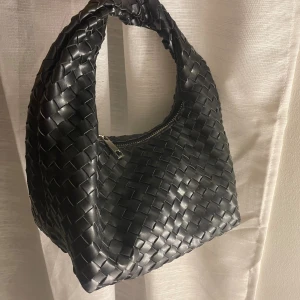 Svart väska  - Flätad svart väska, liknar bottega. Använd men i nyskick. 