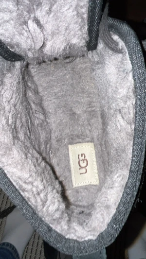 Svarta UGG boots i mocka, storlek 43 - Säljer ett par svarta UGG boots i mocka med snörning och rund tå. Insidan är fodrad med mjuk päls för extra komfort och värme. Sulan är platt och robust, perfekt för kalla dagar. Klassisk UGG-logga på sidan och stilren design som funkar till jeans.