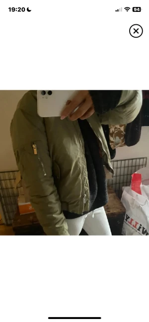 Olivgrön bomberjacka med orange foder - Säljer en olivgrön bomberjacka med orange quiltat foder. Jackan har dragkedja framtill och på ärmen, samt en klassisk loose passform. Perfekt för dig som vill ha en cool och tidlös look. Materialet är troligtvis polyester.