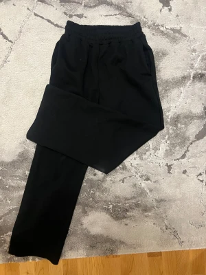  mjukisbyxor från Unionkingdom s/m - Svarta mjukisbyxor från Unionkingdom med elastisk midja och raka ben. Byxorna har fickor på sidorna och en bakficka. 