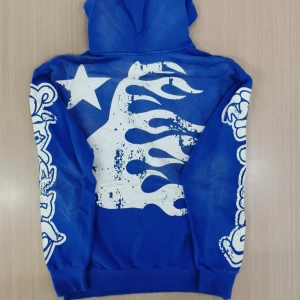 Blå Hellstar hoodie med tryck - Blå hoodie från Hellstar med stora vita tryck på både fram- och baksida samt ärmarna. Tröjan har huva och är tillverkad i 100% bomull. Snygg streetwear-stil med unika grafiska detaljer och stjärnmotiv.