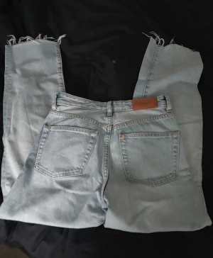Ljusblå high waist jeans från &Denim - Säljer ett par ljusblå jeans från &Denim i rak modell med hög midja. Jeansen har fransade benslut, klassiska fem fickor och snygga sömmar. Perfekt passform för dig som gillar straight fit och vill ha en chill look.