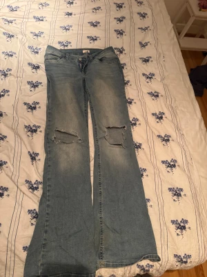 Jeans - Hålet vid ena knät är större då ja råka dra sönder dom och slitna nertill då jag gått på dom.