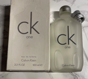 CK One Eau de Toilette 100ml - En klassisk unisexdoft från Calvin Klein. Flaskan innehåller 100 ml eau de toilette och passar perfekt för dig som vill ha en ikonisk och fräsch parfym i din samling.