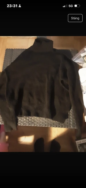 Svart polotröja i stickat material - En svart polotröja i stickat material med lång ärm och klassisk hög krage. Perfekt för lager-på-lager och passar till allt. Enkel och stilren design som funkar året om.