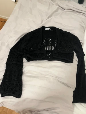Svart bolero från Zara - Svart stickad bolero från Zara med lång ärm och croppad passform.