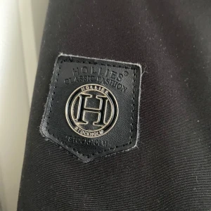 HOLLIES VINTER JACKA ÄKTA PÄLS - Superfin vinterjacka från Hollies med äkta päls. Köpt för 2 år sedan och endast använd en vinter – i nyskick! Jackan är otroligt varm och perfekt för kalla dagar. Den har flera rymliga fickor (mer än två!) som rymmer både mobil och annat du behöver ha med dig. En stilren och kvalitativ jacka som håller dig varm hela vintern