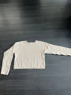 Beige ribbad tröja från Uniq Young - Säljer en beige långärmad tröja från Uniq Young i ribbad design. Tröjan har en rund halsringning och är croppad i modellen, vilket ger en modern och chill vibe. Perfekt för dig som gillar enkla och stilrena plagg med lite edge.