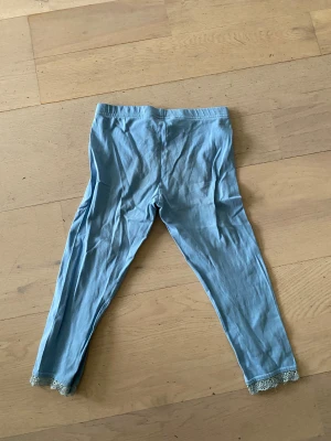 Ljusblå leggings med spets från Index Kids - Säljer ett par ljusblå leggings från Index Kids i storlek 122. De har elastisk midja och är tillverkade i mjuk bomull. Nedtill finns en söt spetsdetalj som ger extra stilpoäng. Perfekta för chill dagar eller när du vill ha något bekvämt.