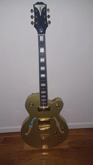 Epiphone Elgitarr - Uptown Kat ES - Topaz Gold Metallic - Epiphone hollow body elgitarr i modell Uptown Kat och färg Topaz Gold Metallic. Nypris 7500kr. Klassisk design och klassigt sound för en rimlig och prisvärd. Enligt många bästa i sin prisklass. Utmärkt skick så gott som mint men har varit använd några gånger. 