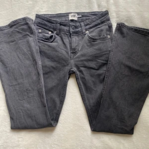 Grå bootcut jeans från 157 - Snygga grå jeans från 157 med bootcut-ben och låg midja. Klassisk femficksmodell med knapp och dragkedja fram. Jeansen har en cool tvättad look och är tillverkade i mjukt denim-material som sitter skönt hela dagen.