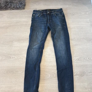 Slim Glenn jeans från Jack & Jones - Mörkblå jeans från Jack & Jones i modellen Slim Glenn. Jeansen har en slim passform, klassisk femficksdesign och snygga slitningar framtill. Tillverkade i bomull med en skön stretch. Perfekta för dig som gillar en smalare siluett och stilren look.