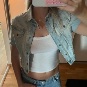 jeansjacka med korta ärmar - Säljer en ljusblå croppad jeansjacka  med korta ärmar. Man kan ha en stickad tröja under. Säljer då den inte kommer till användning 